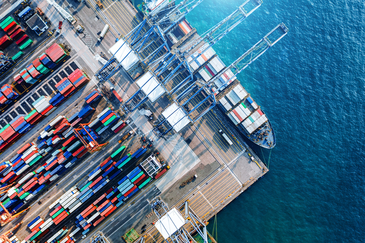 Container cargo freight ship with working crane bridge discharge at container terminal, Drone view container ship at deep sea port.